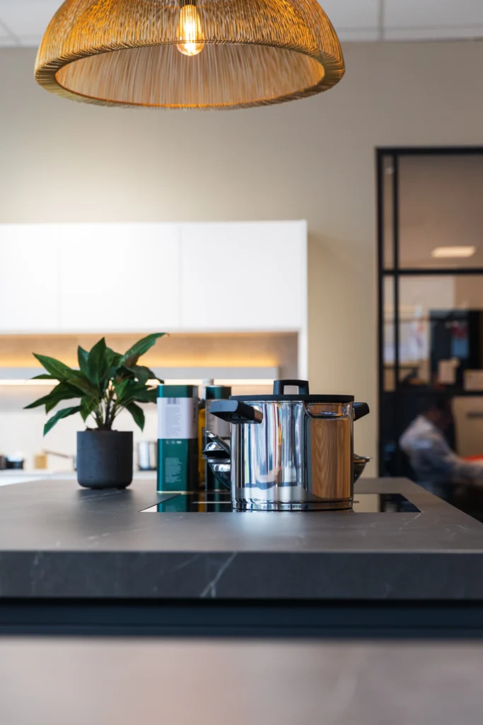 Sfeervolle keukenopstelling met kookboeken, planten en moderne verlichting in showroomomgeving
