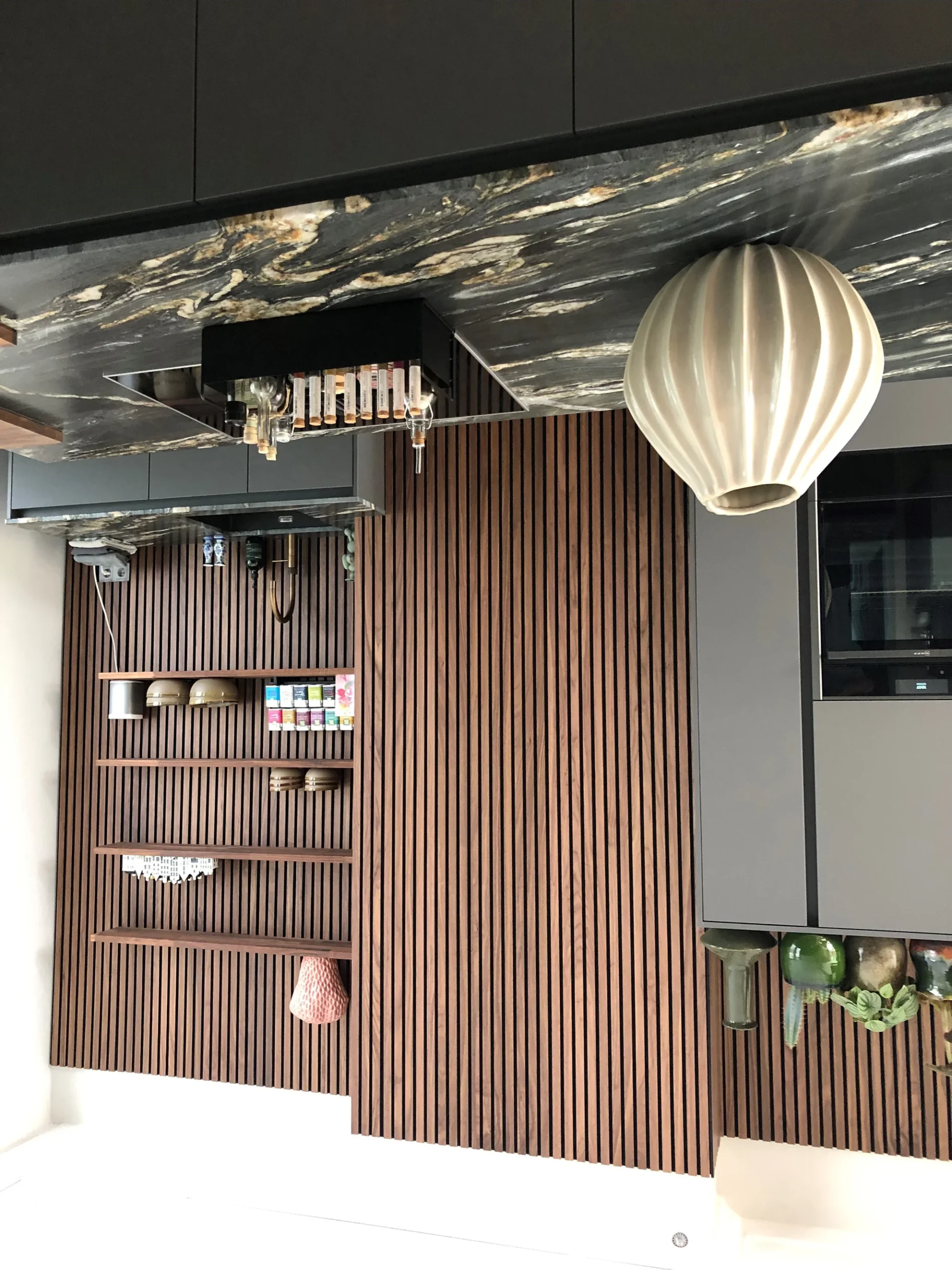 Moderne grijze greeploze keuken met donker granieten werkblad en houten wandaccenten