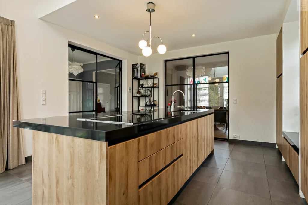 Moderne keuken met zwart granieten werkblad, greeploze zwarte kasten en een ruim kookeiland.