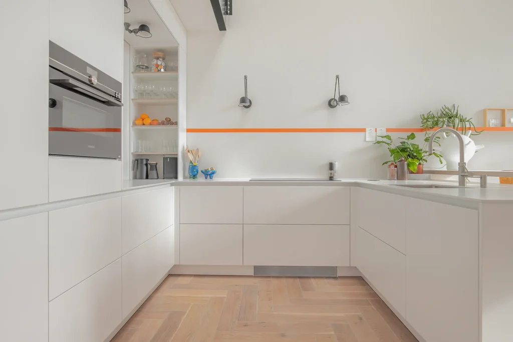 Witte moderne U-vormige keuken met greeploze fronten en een wit stenen werkblad.