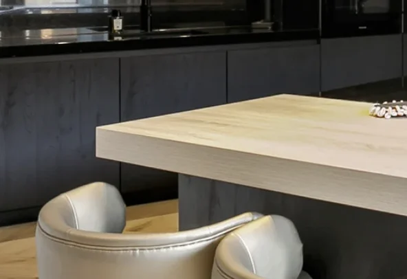 Moderne keuken met licht houten tafelblad en zilverkleurige ronde stoel bij een donkere kastwand