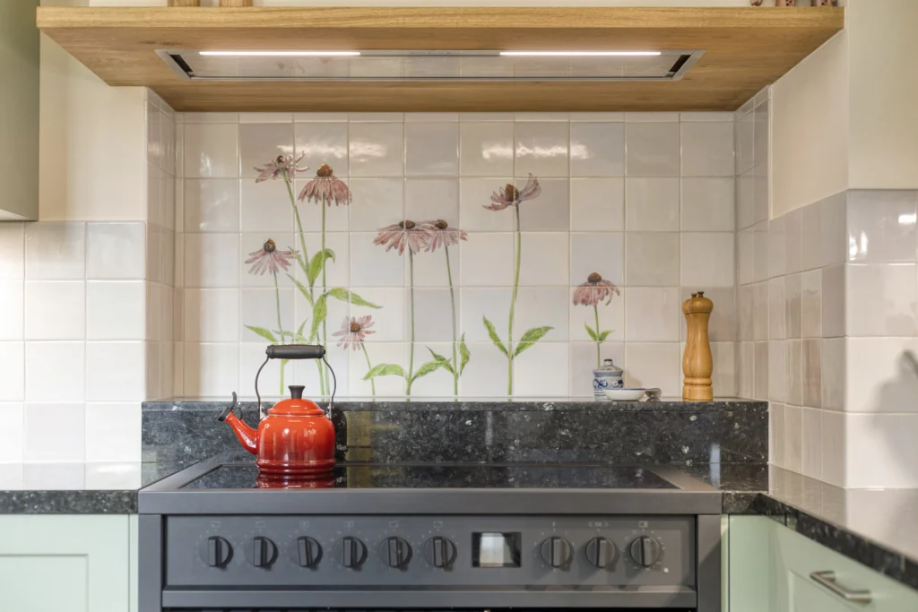 Moderne keuken met keramische bloementegels, felrode waterketel en lichtgekleurde kasten