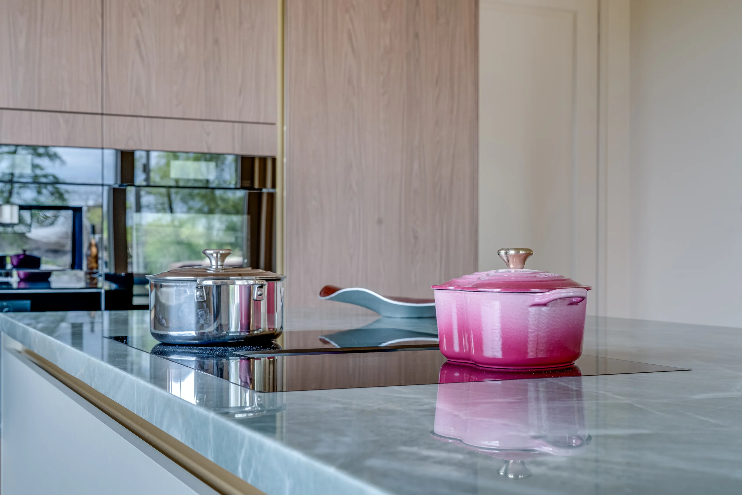 Een moderne keuken met lichtkleurige tafel met twee pannen, roestvrijstalen en roze met gouden knop
