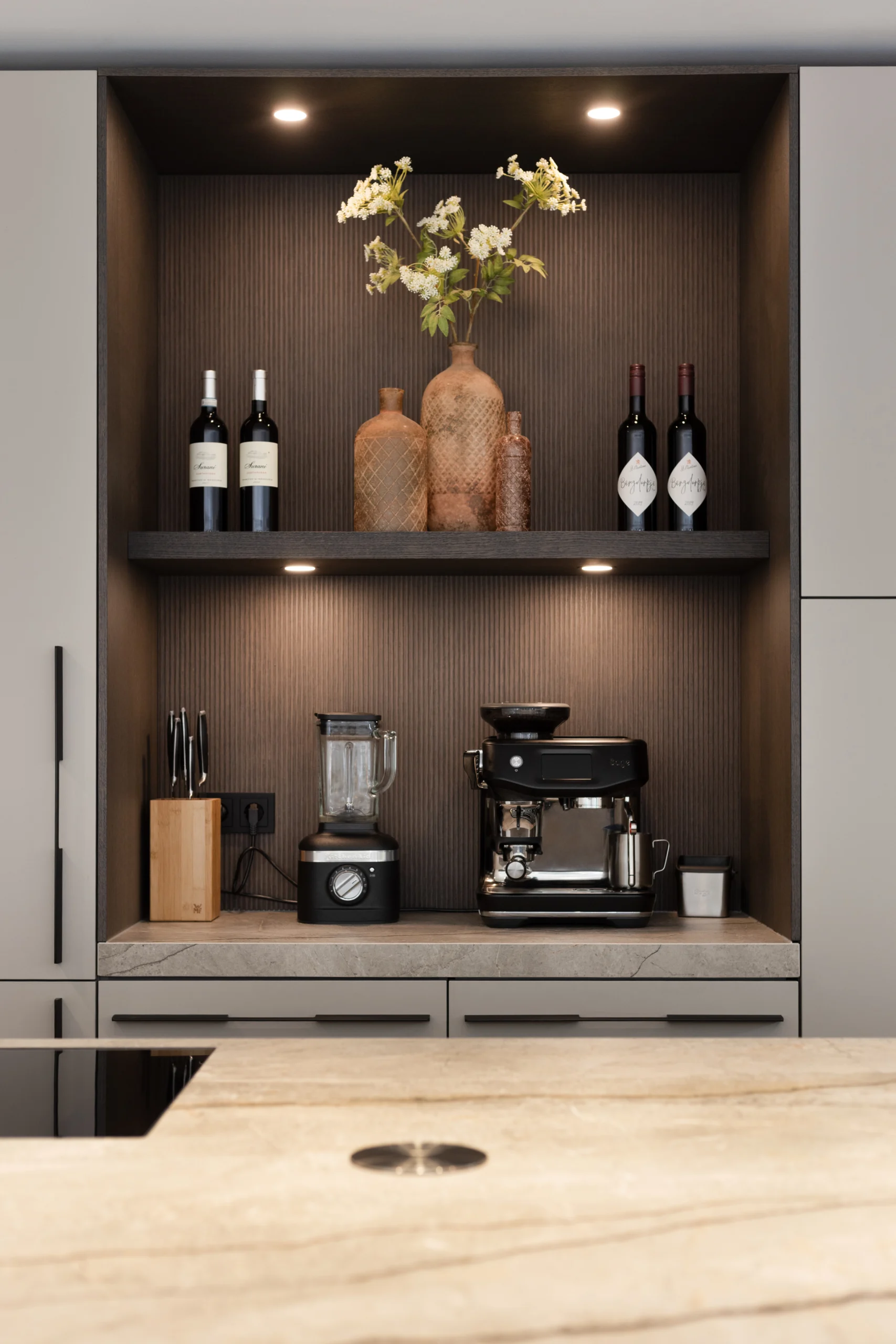 Moderne keuken met open kast, twee planken, wijnflessen, vazen, blender en espressomachine