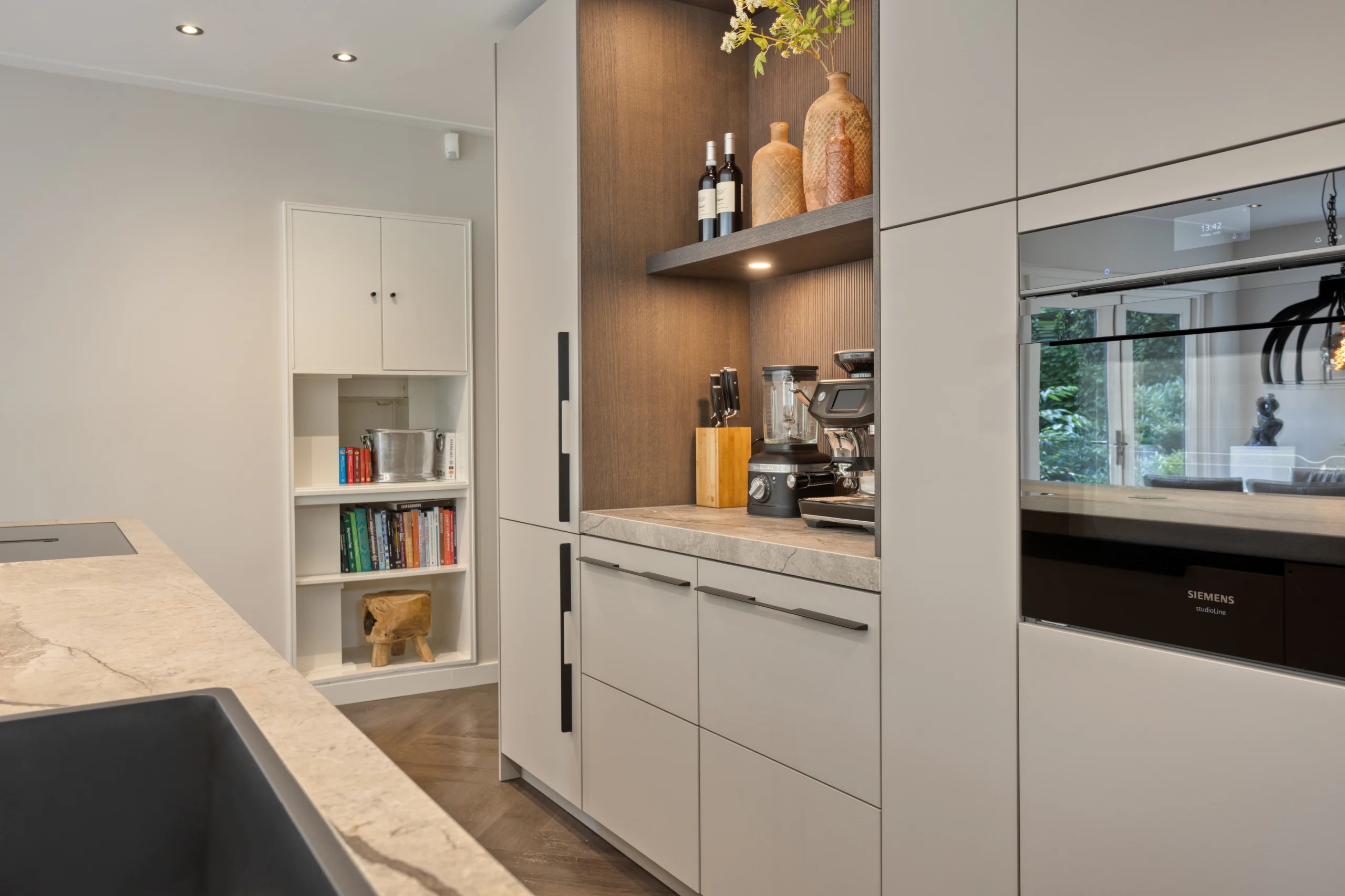 Moderne keuken met licht stenen keukenblad, keukenkasten in lichte en donkere tinten, en decoratieve vazen bovenin