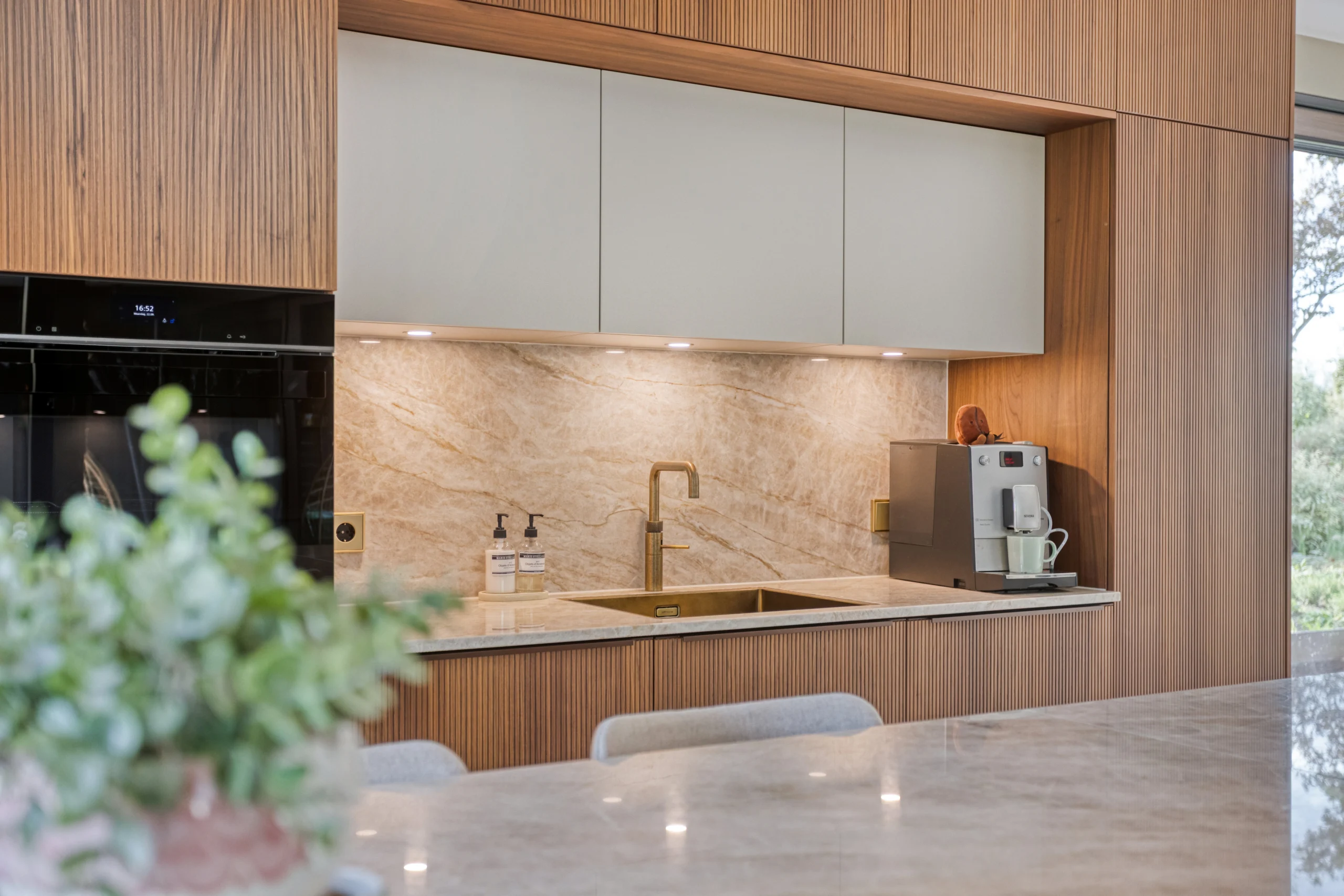 Moderne keuken met houten bovenkasten, marmeren achterwand en gootsteen met gouden kraan